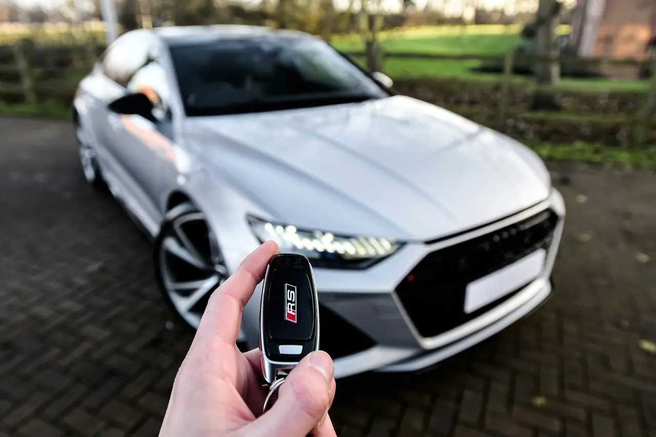 Holding up the key in front of a silver Audi
